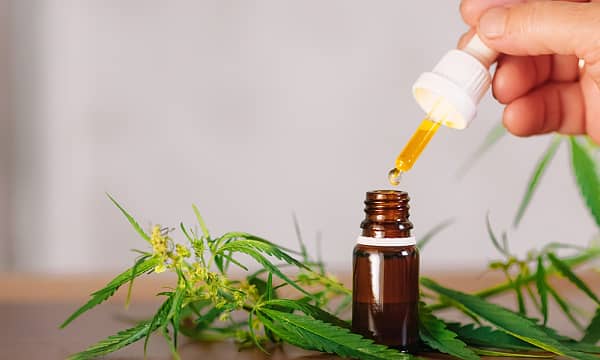 Pros and Cons of CBD for pain, A person holding a CBD bottle to take for pain.
